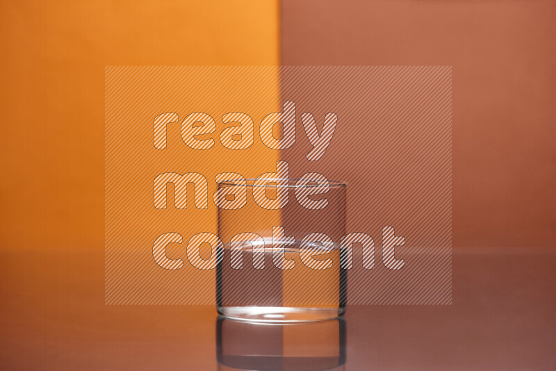 The image features a clear glassware filled with water, set against orange and dark orange background