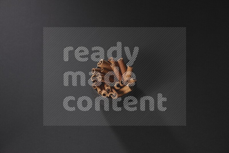 Cinnamon sticks in a black bowl on a black background in different angles
