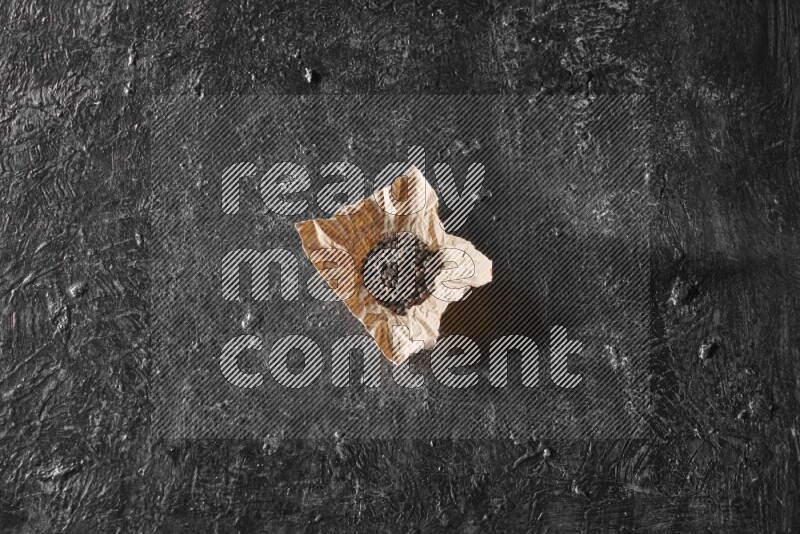 حبوب الفلفل الأسود في قطعة من الورق علي خلفية سوداء