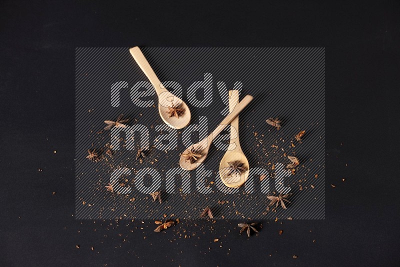 Star Anise in wooden spoons on black flooring