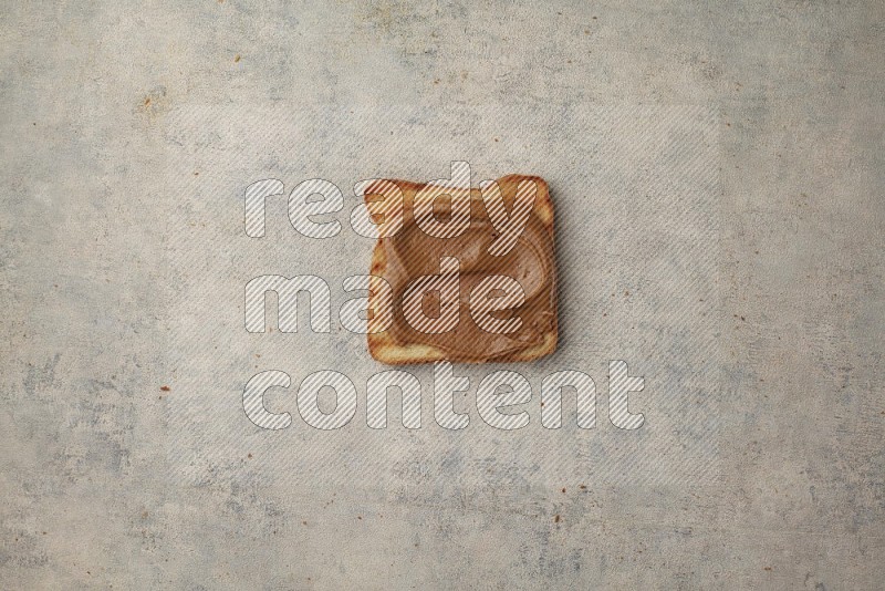 Creamy peanut butter on a toasted white toast slices on a light blue textured background