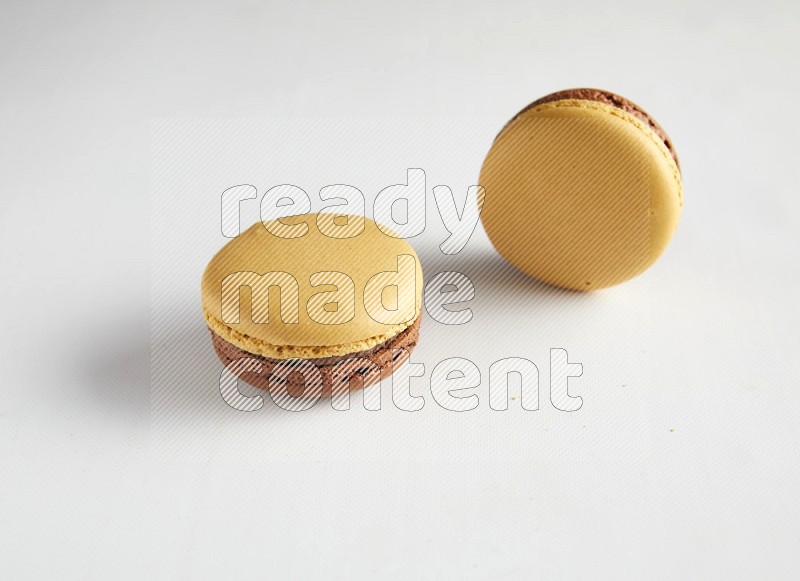 45º Shot of two Yellow and Brown Chai Latte macarons on white background