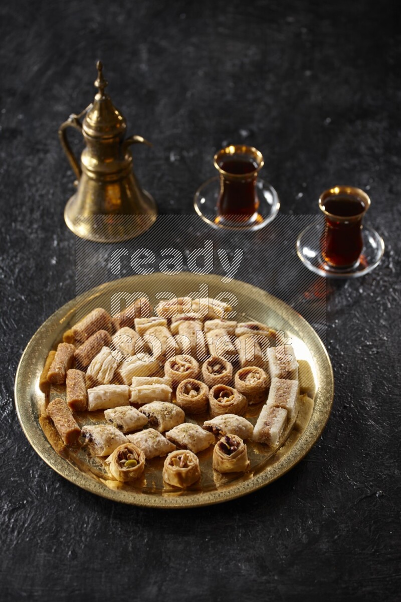 Oriental desserts with tea and a metal pot in a dark setup