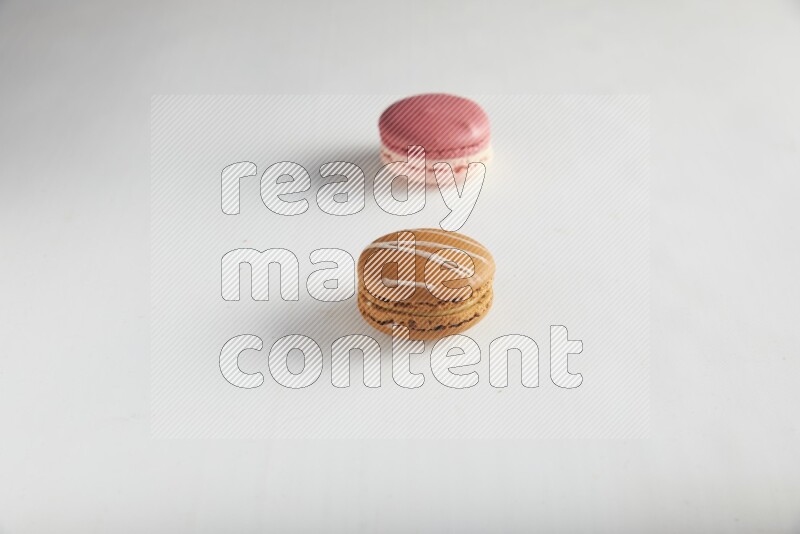 45º Shot of of two assorted Brown Irish Cream, and Pink Litchi Raspberry macarons on white background