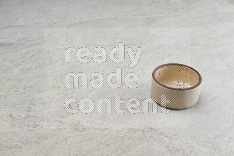 A beige pottery oven bowl on grey marble background