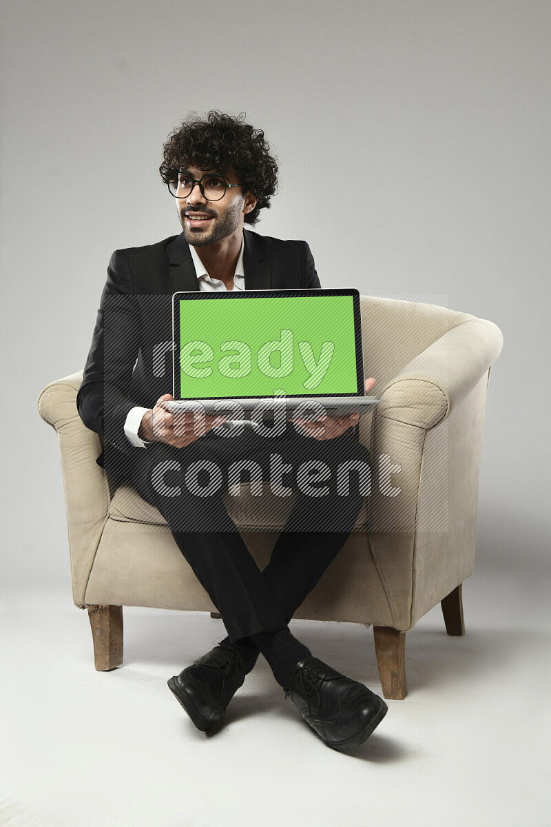A man wearing formal sitting on a chair showing a laptop screen on white background