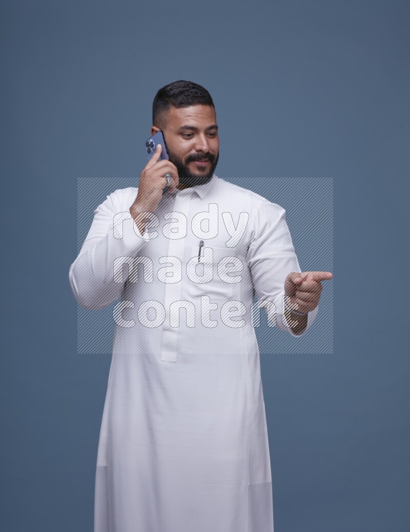 A Saudi man calling on blue background wearing Saudi Thob