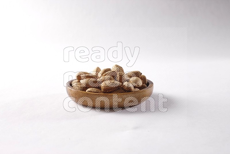 Almonds in a wooden bowl on white background