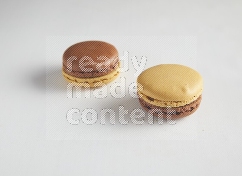 45º Shot of two Yellow and Brown Chai Latte macarons on white background