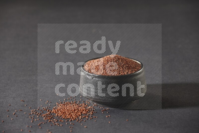 وعاء فخاري أسود ممتلئ ببذور حب الرشاد على أرضية سوداء