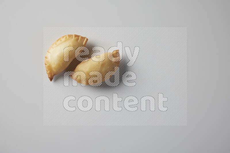 Two fried sambosa from a top angle on a white background