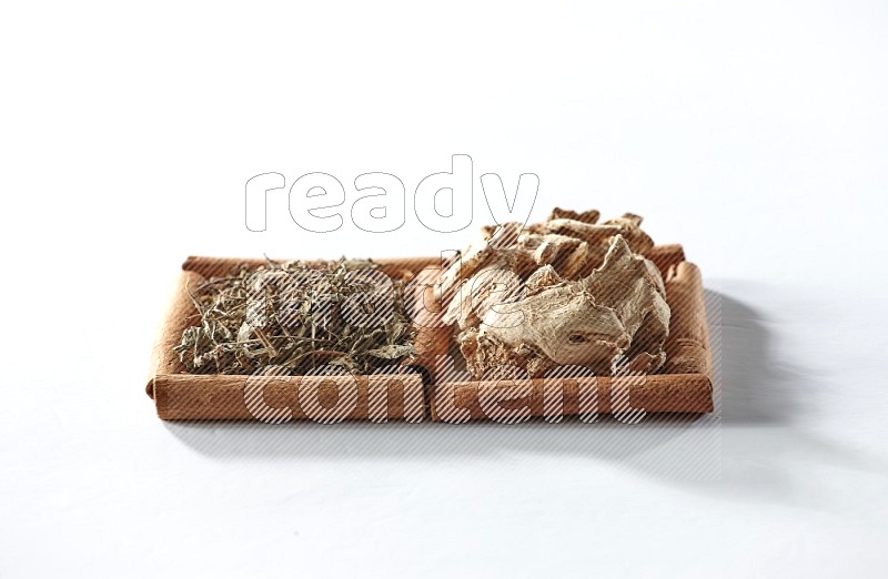 2 squares of cinnamon sticks full of dried ginger and dried basil on white flooring