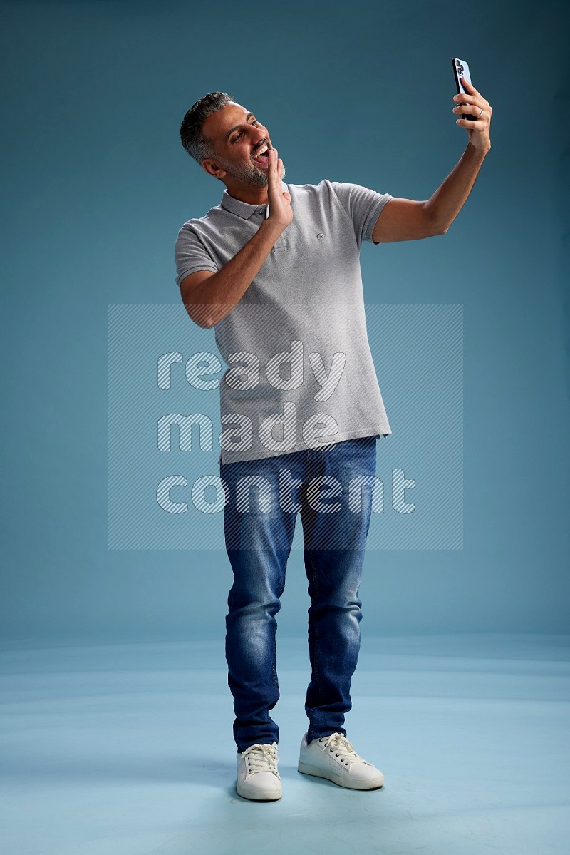 Man Standing taking selfie on blue background