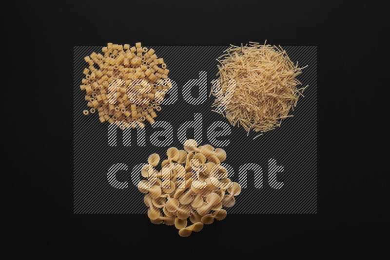 Different pasta types in bunches on black background