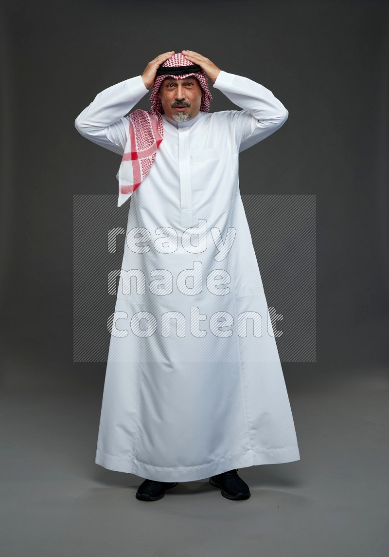 Saudi man with shomag Standing Interacting with the camera on gray background