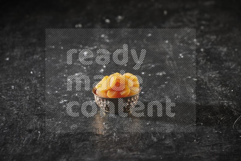 Dried fruits in a metal bowl in a dark setup