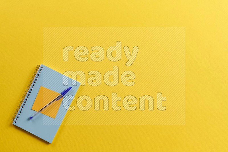 A blue notebook with school supplies on yellow background (Back to school)