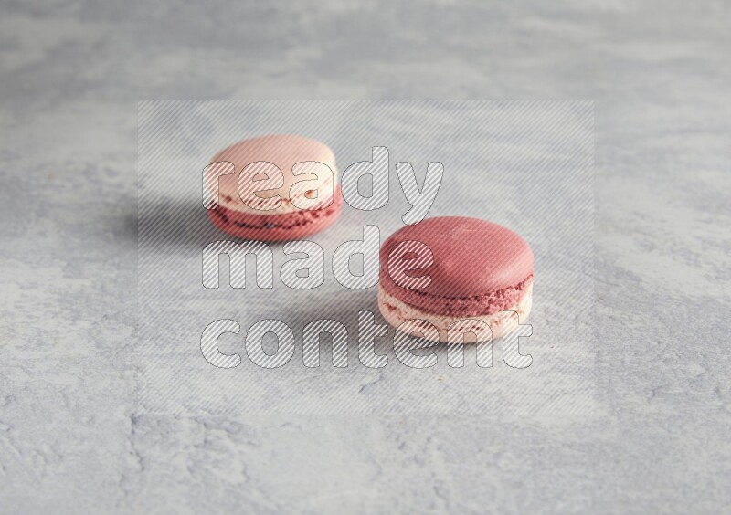 45º Shot of two Pink Litchi Raspberry macarons  on white  marble background