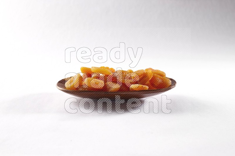 Dried apricots in a wooden plate on white background