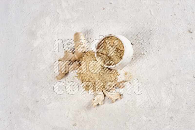 A beige pottery bowl full of ground ginger powder with fallen powder from it on white background