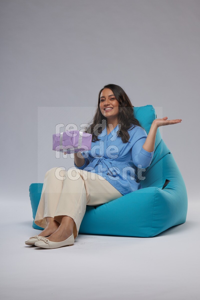A woman sitting on a blue beanbag and holding a gift