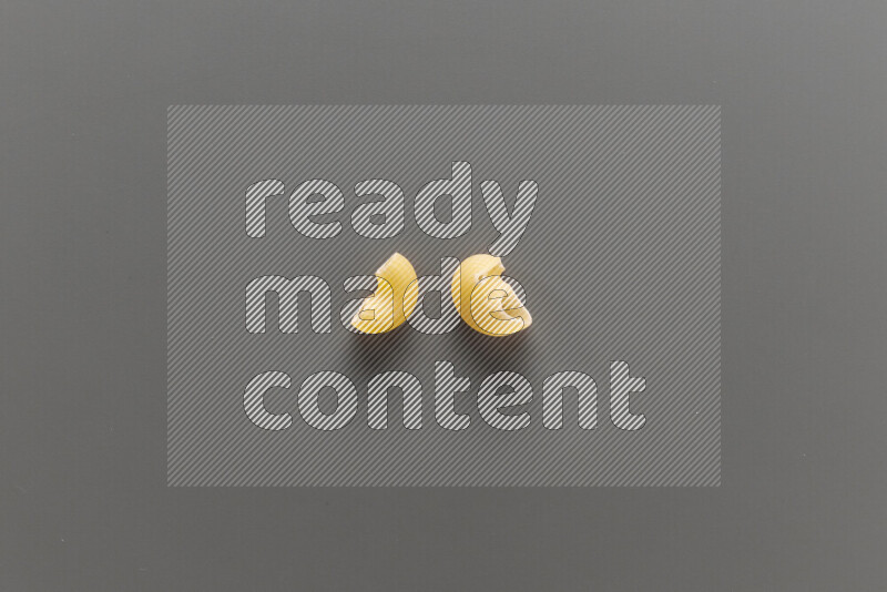 Elbow pasta with other types of pasta on grey background