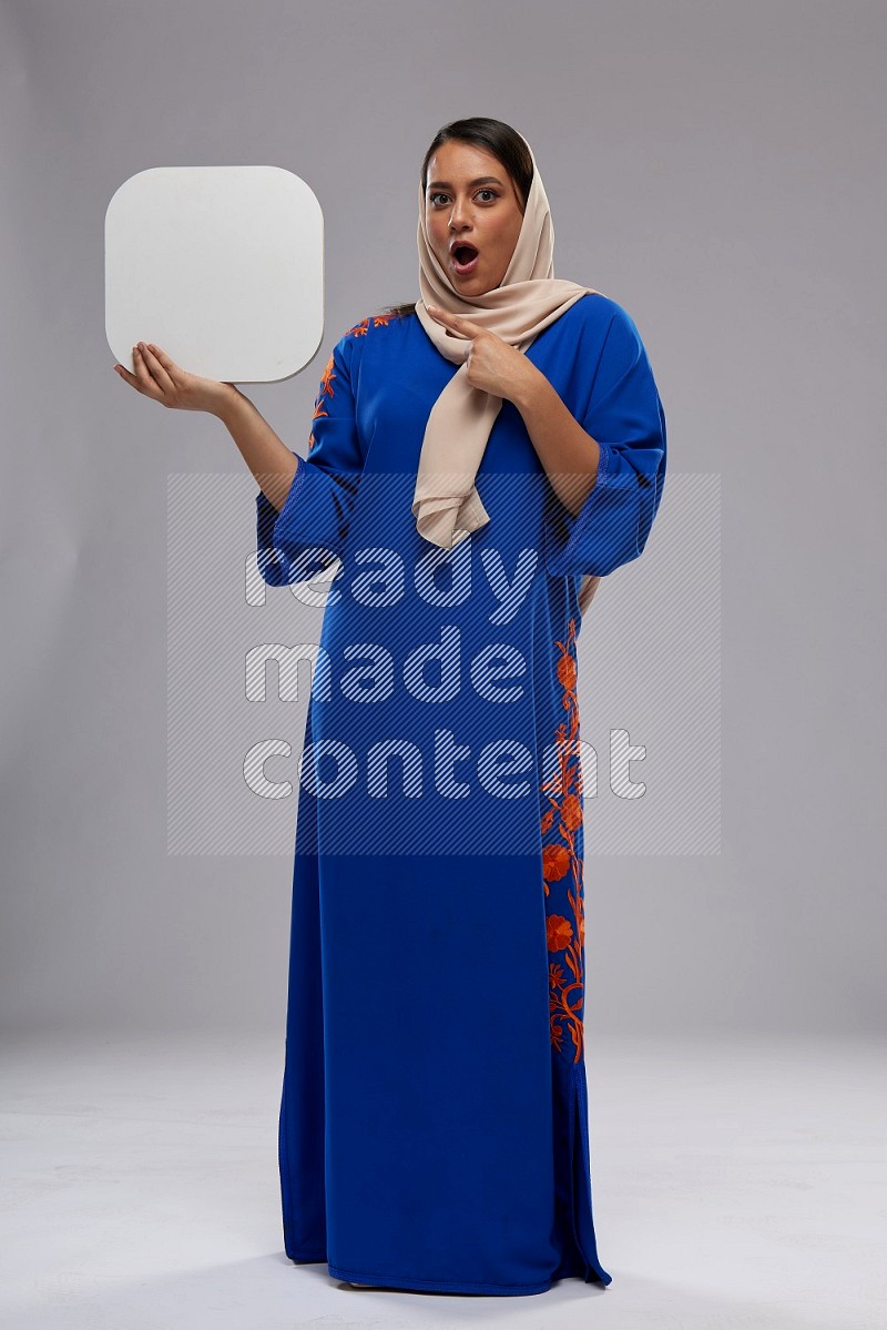 A Saudi woman standing wearing Jalabeya holding a social media sign
