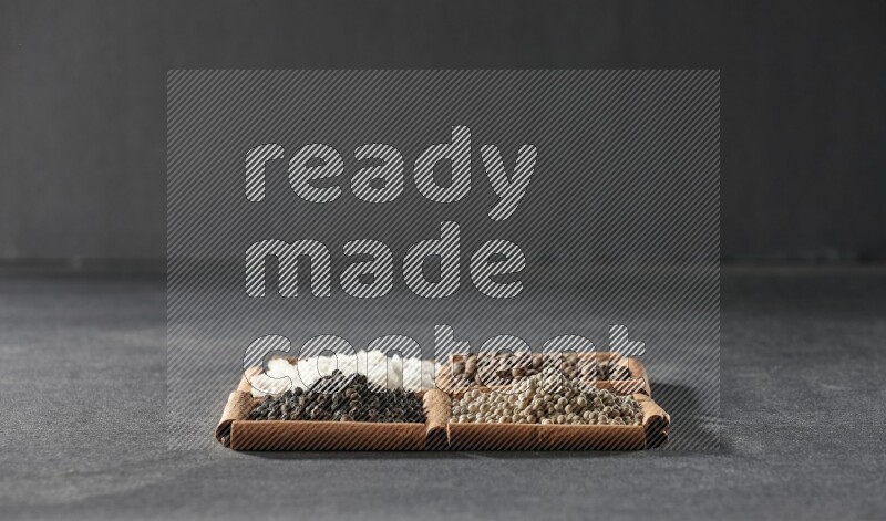 4 squares of cinnamon sticks full of black pepper, white pepper, allspice and white salt on black flooring