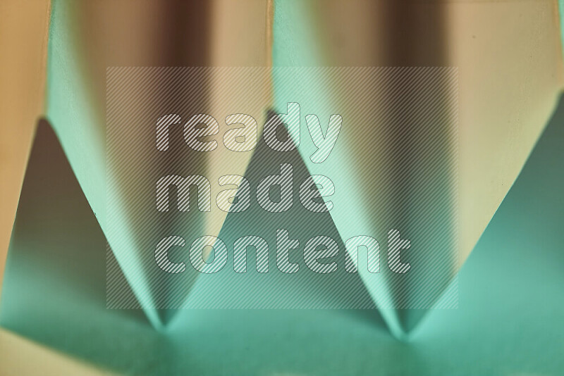 صورة مجردة مقربة تظهر طيات ورقية هندسية حادة بتدرجات اللون الأخضر مع درجات لونية دافئة