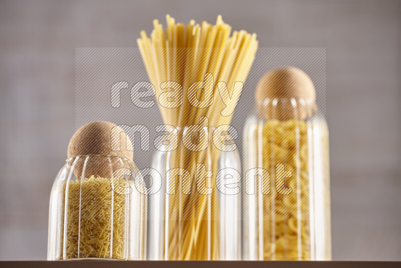 Raw pasta in glass jars on beige background