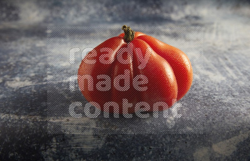 45 degree single heirloom tomato on a textured rustic blue background