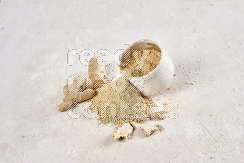 A beige pottery bowl full of ground ginger powder with fallen powder from it on white background