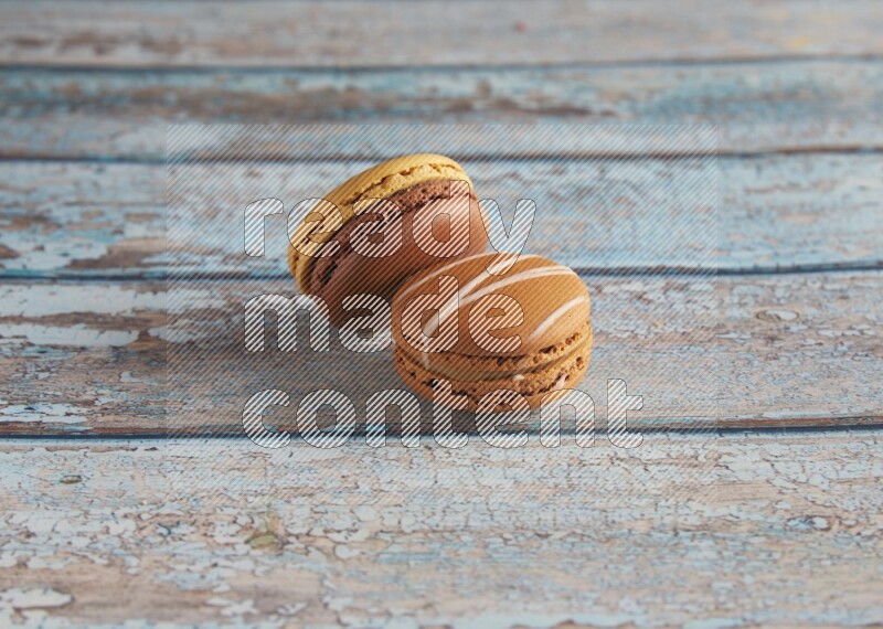 45º Shot of of two assorted Brown Irish Cream, and Yellow, and Brown Chai Latte macarons  on light blue background