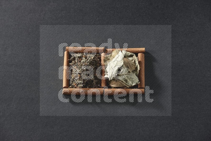 2 squares of cinnamon sticks full of bay laurel leaves and dried basil on black flooring