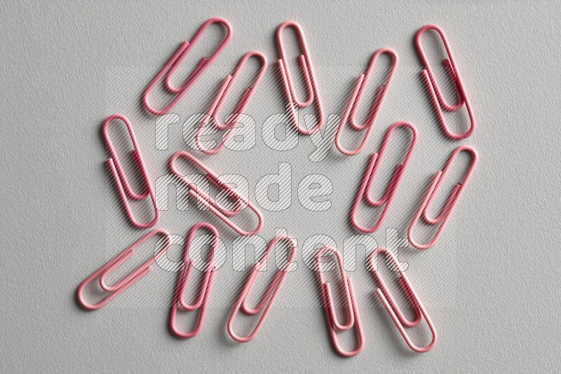 Pink paper clips isolated on a grey background