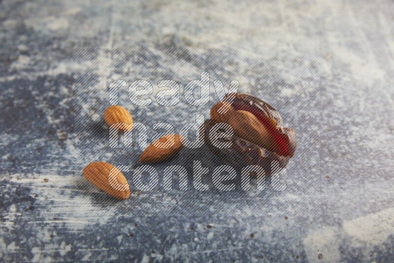 one almond stuffed madjoul dates on a rustic blue background