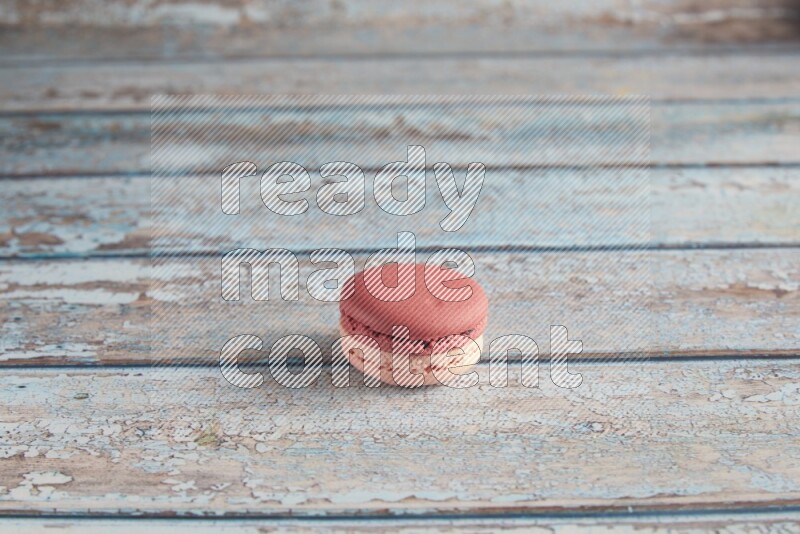 45º Shot of Pink Litchi Raspberry macaron on light blue wooden background