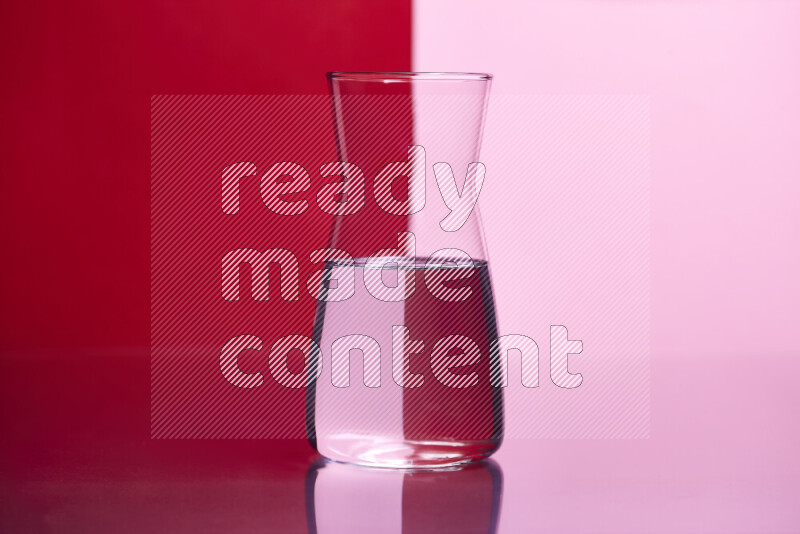 The image features a clear glassware filled with water, set against red and rose background