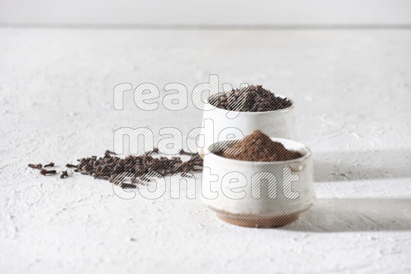 وعاءين من السيراميك بيج اللون، أحدهما مملوء بالقرنفل والآخر مملوء بالبودرة على أرضية بيضاء