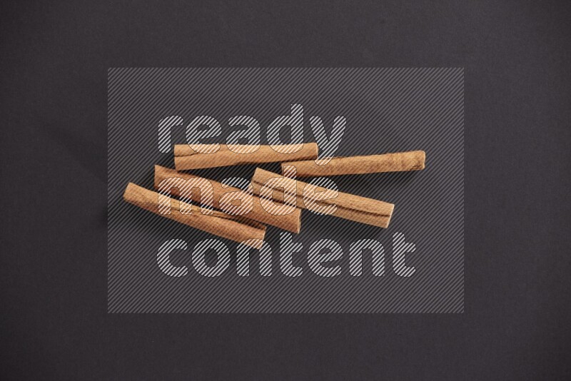 Cinnamon sticks stacked on black flooring