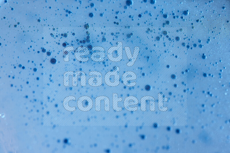 لقطات مقربة لقطرات ألوان مائية زرقاء على سطح الزيت على خلفية زرقاء