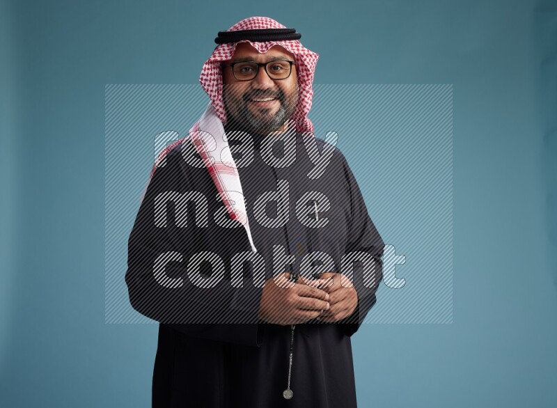 Saudi Man with shimag Standing Interacting with the camera on blue background