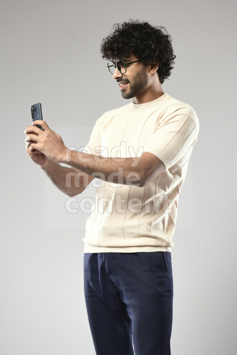 A man wearing casual standing and shooting with his phone on white background