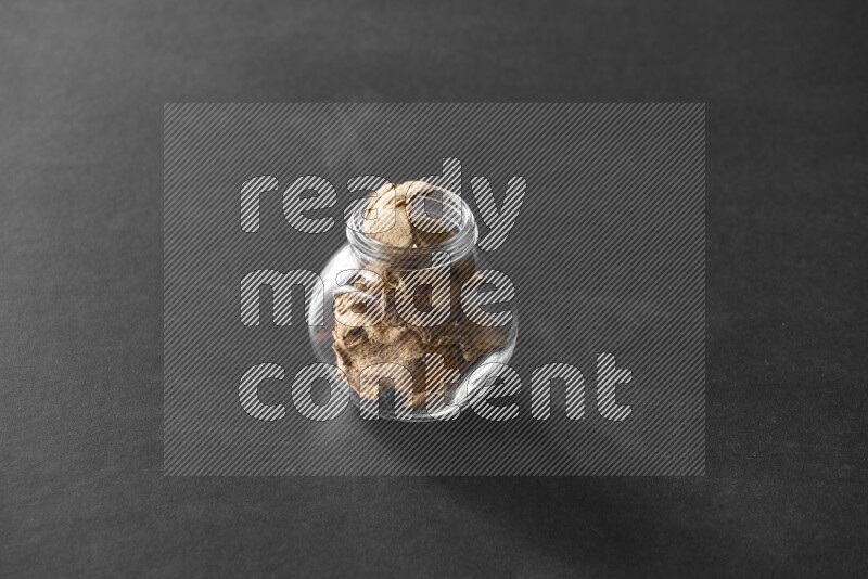 A glass spice jar full of ginger on black flooring