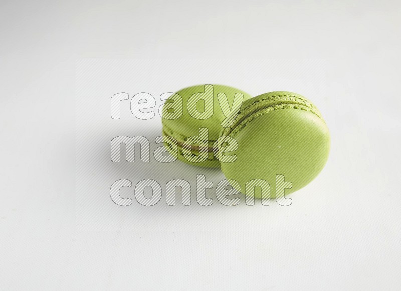 45º Shot of two Green Pistachio macarons on white background