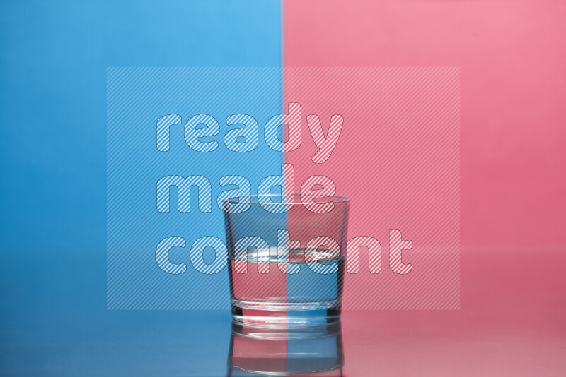 The image features a clear glassware filled with water, set against blue and pink background