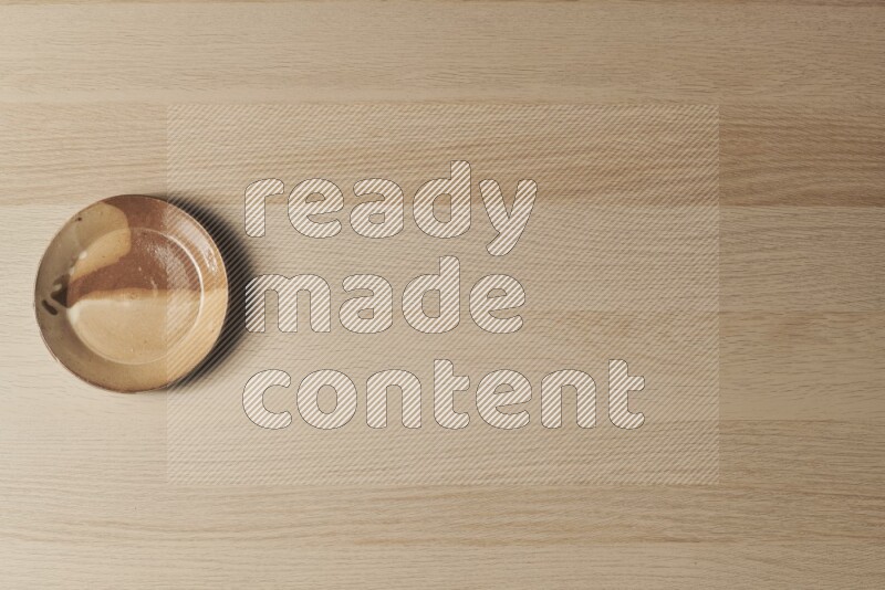 A multicolored pottery plate on light wooden background