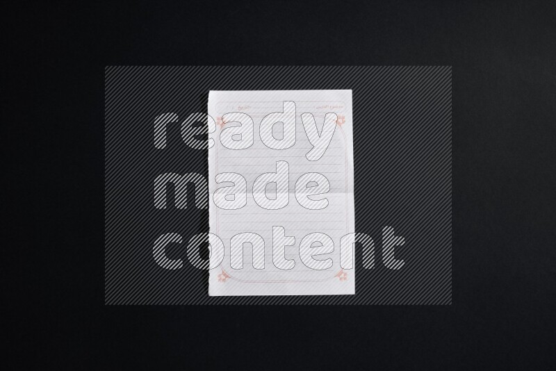 Folded notebook sheet on black background