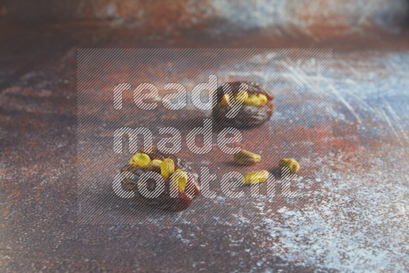two pistachio stuffed madjoul dates on a rustic reddish background
