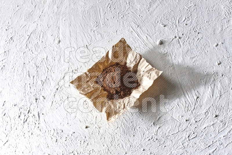 Cloves powder on crumpled piece of paper on a textured white flooring